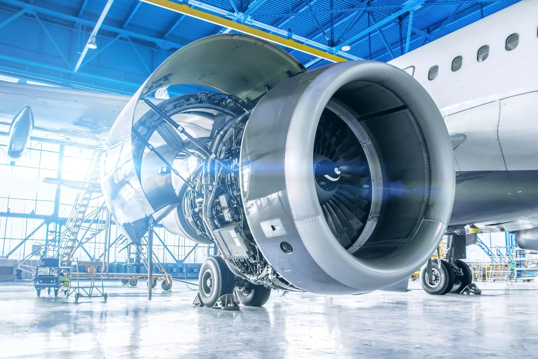 An airplane inside of a hangar, with its engine compartment opened up. 