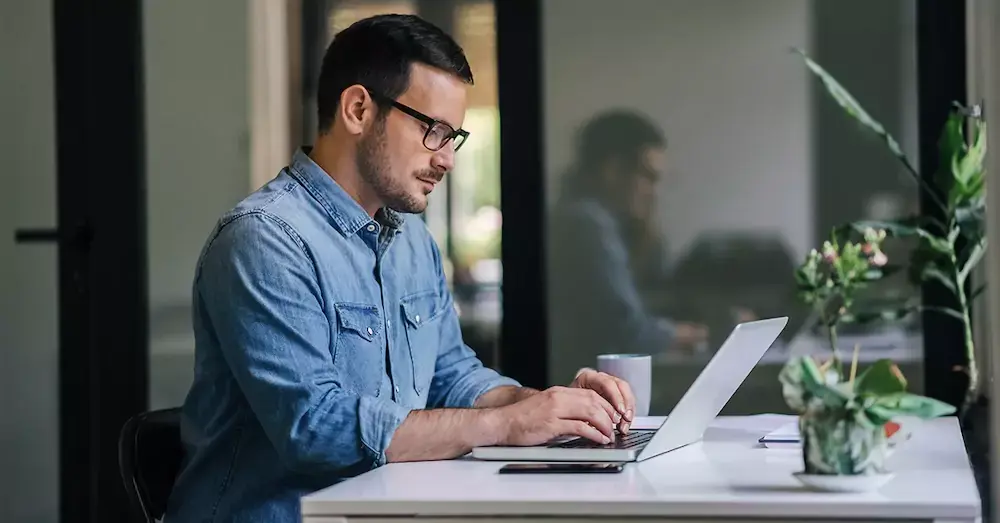 A man in glasses on a computer.