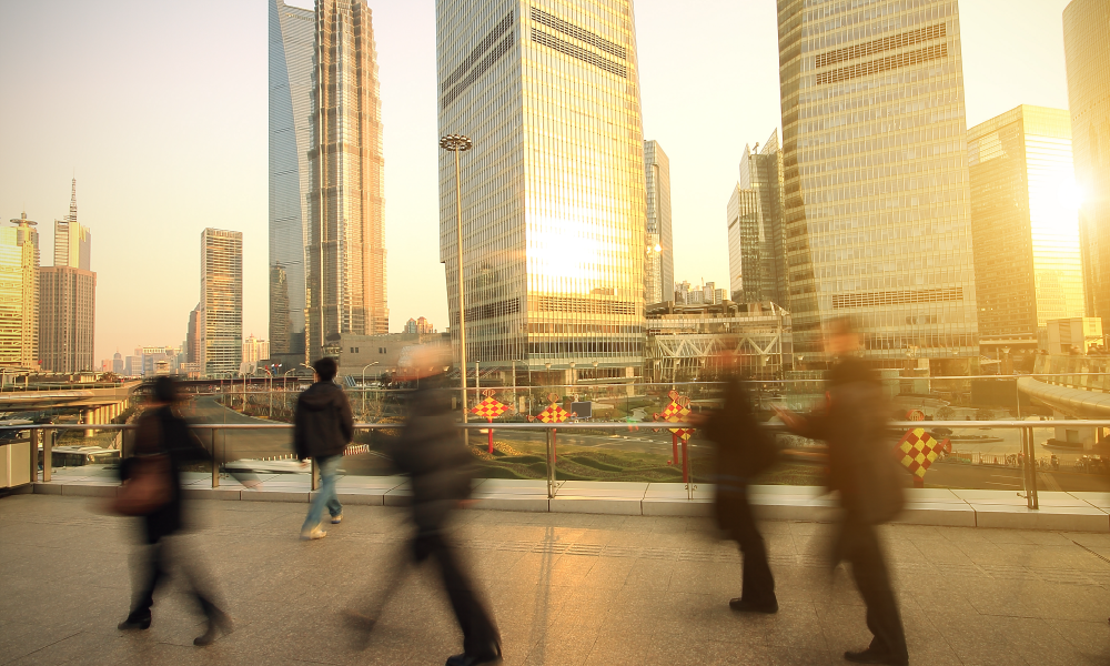 A photo of people walking on the street in Shanghai at sunset. Motion blurs the figures of people moving quickly. 