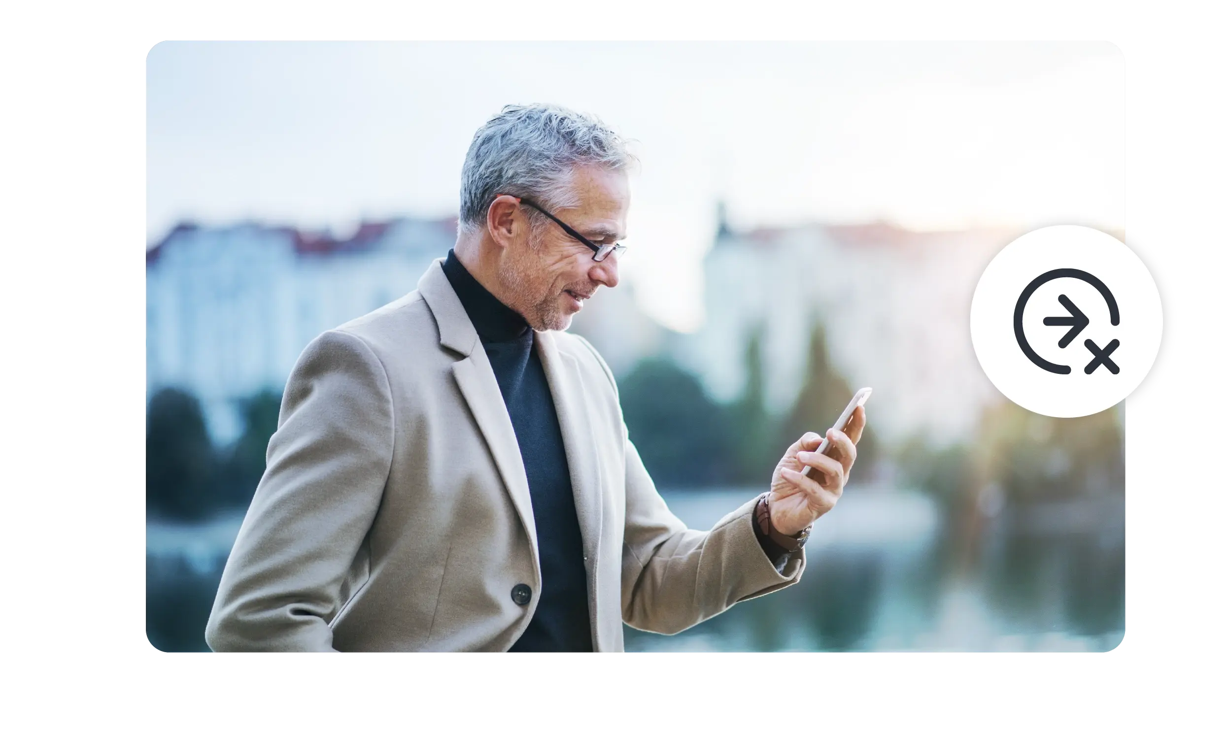 A man walks down the street in a European city, looking at his phone. 